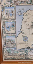Load image into Gallery viewer, Antique map showing the town of Marblehead, Massachusetts, at center with illustrations of notable buildings and notable ships in the sea. Surrounding the map are scenes historical events and local industries like fishing. Colors of buttery light yellow, green, and light blue. Decorative scrollwork, fishes, lobsters, and the town seal. Framed in a vintage medium-tone wood frame