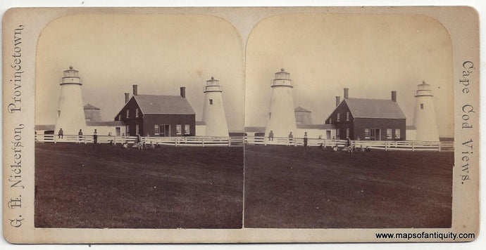 Antique card with two nearly identical images showing the original CHatham Lighthouses aka twin lights with the dark colored keepers building between them and a white fence upon which figures sit, lean, and stand with a grouping of seated figures in the grass in front of the fence. Photo was taken at a distance and the figures features are not discernable. 